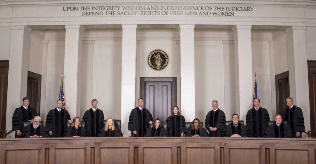 The current 15 judges for the Court of Appeals of the State of Georgia seated and standing behind the bench in the court room of of the Nathan Deal Judicial Center.